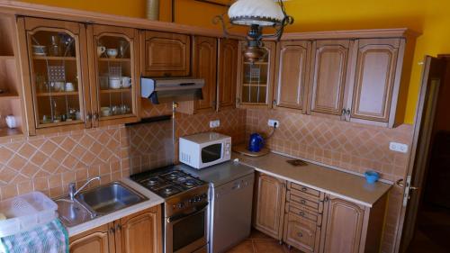 a kitchen with wooden cabinets and a stove and a microwave at Lipták Vendégház in Tokaj