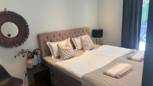 a bedroom with a bed with pillows and a mirror at Beachfront apartment with private swimming dock in Asker
