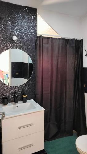 a bathroom with a black shower curtain and a sink at Dar Amora in Ras El Ma