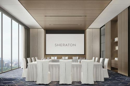 a conference room with a long table and white chairs at Sheraton Kunshan Dianshan Lake in Kunshan