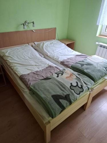 a bed with a blanket on it in a bedroom at Roman Tarnawa "Nasz Domek" in Szczytna