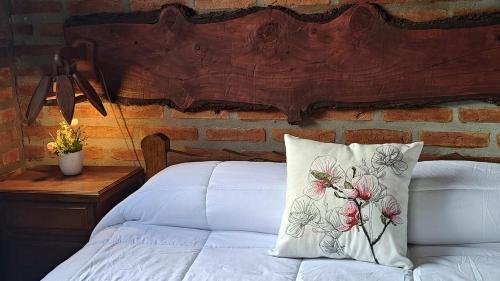 Un dormitorio con una cama blanca con una pared de ladrillo. en Cabañas Don Fernando, en Santa Rosa de Calamuchita