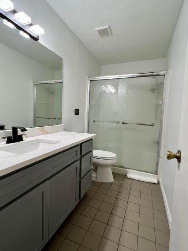a bathroom with a sink and a toilet and a mirror at By Popular Demand - Houston in Houston