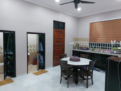 a dining room with a table and a kitchen at Zmz Homestay in Pasir Mas