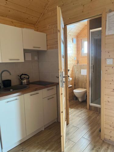 a kitchen with white cabinets and a toilet in a room at Zacisze Za Lasem in Jarosławiec