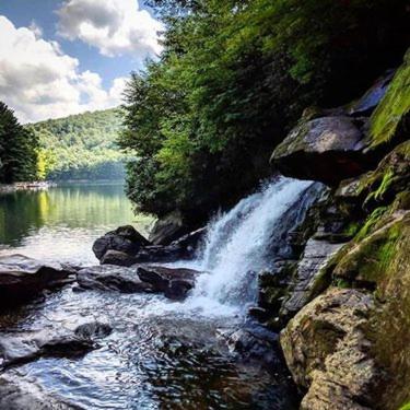 a waterfall on the side of a river at Bungalow, Lake Glenville, Amazing Views, & Sauna! in Cullowhee