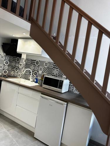 Duplex proche Arènes في نيم: مطبخ بخزائن بيضاء وميكروويف على سطح العمل