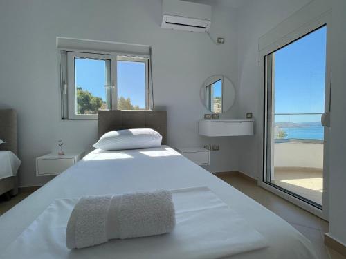 a white bedroom with a large bed with a large window at Villa Er Deti in Sarandë
