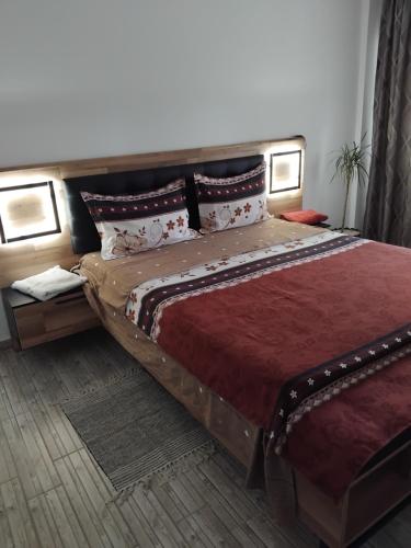 a bedroom with a large bed with red sheets and pillows at Apartament Manu 2 dormitoare in Târgu Neamț
