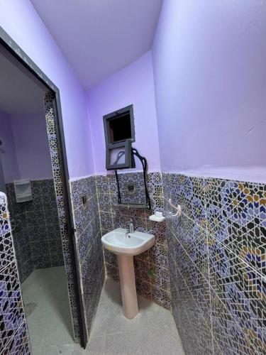 a bathroom with a sink and a tv on the wall at Cafe Restaurant Moove Oil in Rissani