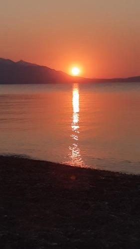 a sunset over a body of water with the sun setting at Rooms Magnolia in Nea Vrasna