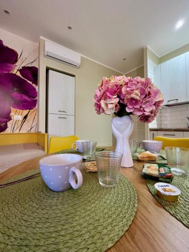 a table with a vase with pink flowers on it at Vista Mare Luxury Rooms & Apartments in Margherita di Savoia