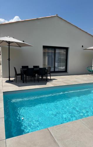 une piscine avec une table, des chaises et un parasol dans l'établissement Villa avec piscine en Provence, à Les Mées