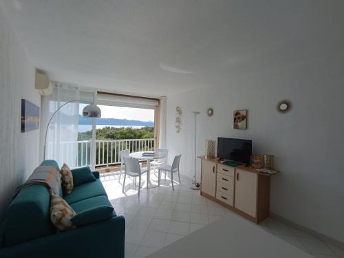 ein Wohnzimmer mit einer Couch und einem Tisch mit einem Fernseher in der Unterkunft studio cosy vue mer in Patrimonio