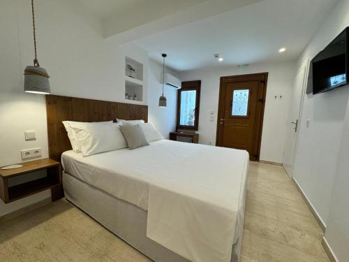 a bedroom with a large white bed and a television at Kalami in Kokkari