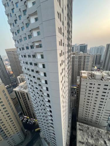 a tall white building in a city with tall buildings at AlNahda Border SHJ-DXB -ZAMAZM GuestHouse in Sharjah