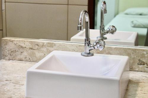 a bathroom sink with a faucet in front of a mirror at Pousada Carnaúbas - Sobral in Sobral