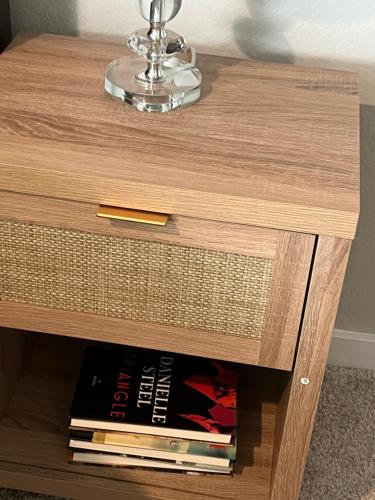 a wooden bedside table with books on it at Nanashortlet in Rosenberg