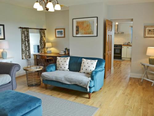 a living room with a blue couch and a kitchen at Havannah Cottage in Alnham