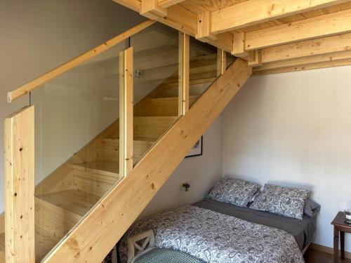 a loft bed with a bed underneath a wooden staircase at Le Petit Palais in Escarrilla