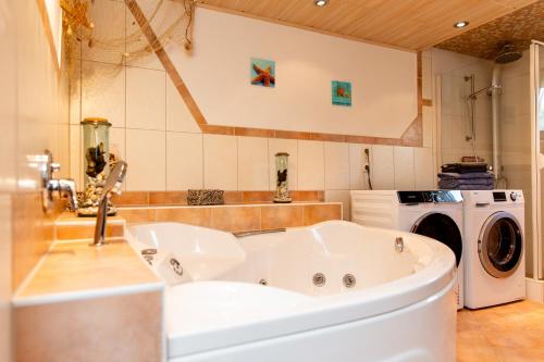 a bathroom with a tub and a washing machine at Ferienwohnung 70qm - Natur, Fitness & SUP am Fluss in Damm