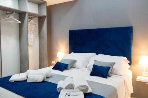 a bedroom with a large white bed with blue accents at Scugnizzo Apartment SMART in Naples