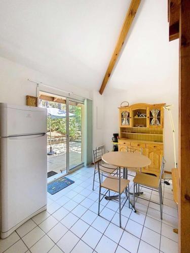 une cuisine avec une table et un réfrigérateur dans l'établissement Résidence Jardins De L'ocean - Pavillon mitoyen 1 chambre + mezzanine, 4 pers, résidence avec piscine MAE-0641, à Lacanau