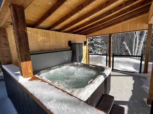 a jacuzzi tub on a deck with snow at Chalet au pic du bois in Saint-Calixte
