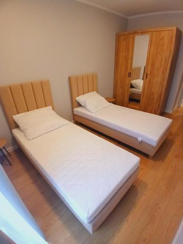 two beds in a room with a mirror at Słoneczny Apartament in Kłodzko