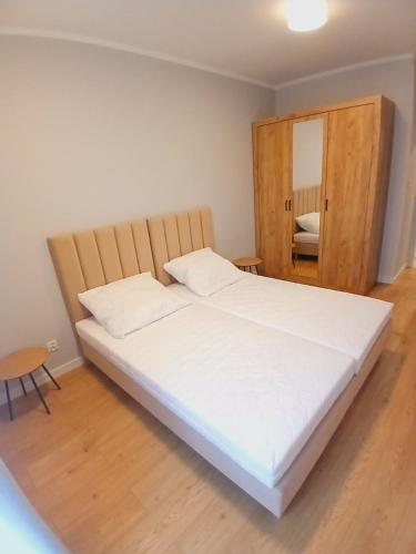 a bedroom with a large white bed with a wooden headboard at Słoneczny Apartament in Kłodzko