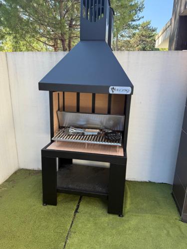 a barbecue grill with a blue hood on a patio at Villa Pinewood in Lignano Sabbiadoro