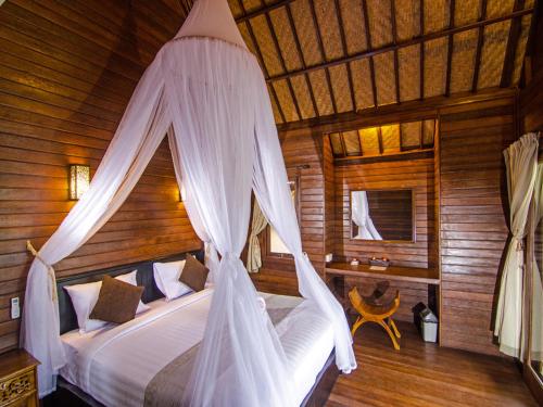 a bedroom with a bed with a mosquito net at Cassava Bungalow in Nusa Lembongan