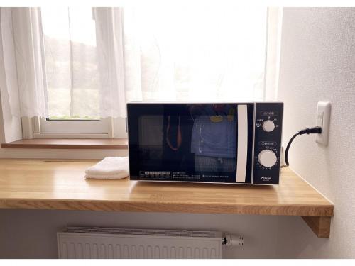 a microwave sitting on top of a wooden counter at Hotel Hanafuji Inn - Vacation STAY 61010v in Nakafurano
