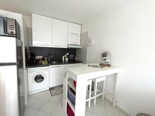 eine Küche mit weißen Schränken und einer Waschmaschine in der Unterkunft studio cosy vue mer in Patrimonio