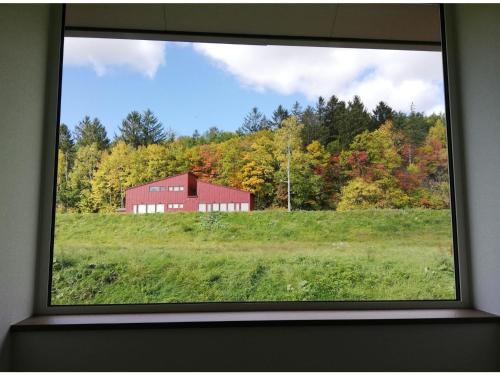 a window view of a red barn in a field at Hotel Hanafuji Inn - Vacation STAY 61010v in Nakafurano
