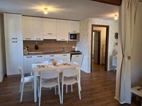 a kitchen with a white table and white chairs at Casa Jedi in Santa Maria Maggiore