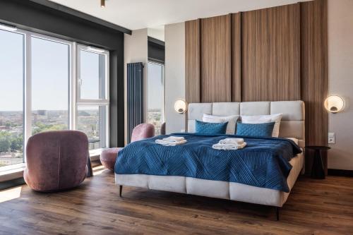 a bedroom with a large bed with blue sheets and windows at SAUNA JACUZZI River View QUORUM Apartment in Wrocław