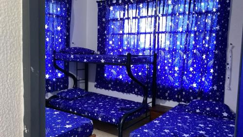 a room with three bunk beds in front of a window with blue lights at casa maranatha in Melgar