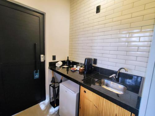 a small kitchen with a sink and a refrigerator at Hotel Boutique Vinícola Araucária by Slaviero Hotéis in São José dos Pinhais
