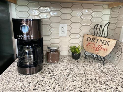 a coffee maker on a counter with a drink coffee sign at Central NWA-Games, Concerts, Nature and More in Lowell