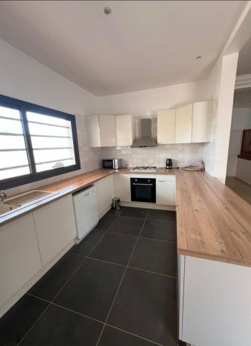 a kitchen with white cabinets and a black tile floor at Villa Le charme de Somone in Somone