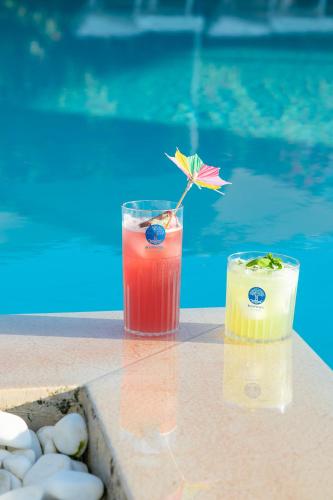 two cocktails sitting on a table next to a pool at Boomerang Village in Torre Colimena
