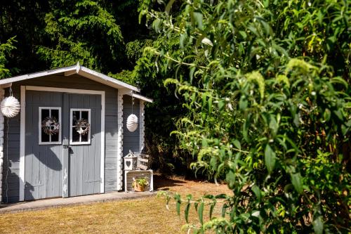 a small grey shed with a window in a yard at Ferienwohnung 70qm - Natur, Fitness & SUP am Fluss in Damm