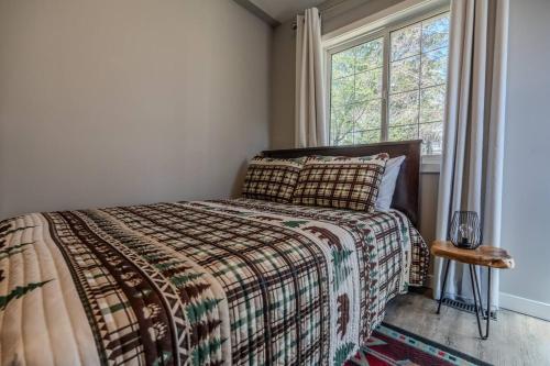 a bedroom with a bed with a blanket and a window at The Riverside Retreat at Fairmont in Fairmont Hot Springs