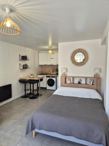 a bedroom with a bed and a table and a kitchen at Studio Bohême chic à Disney in La Houssaye-en-Brie
