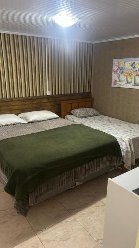 two beds in a hotel room with a green blanket at Morada da Floresta in Gramado