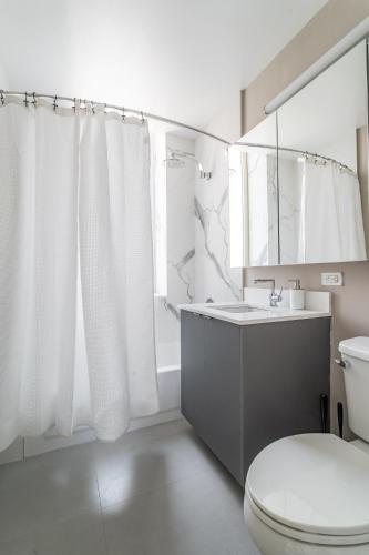 a white bathroom with a toilet and a sink at Chic NYC Stay Steps from Times Square with 2 bedroom in New York