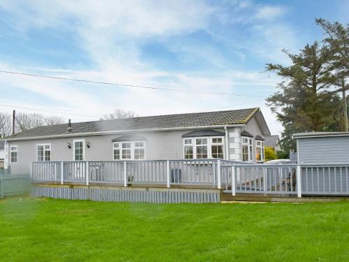 a white house with a fence and a yard at Eryl Mor Lodge in Amlwch
