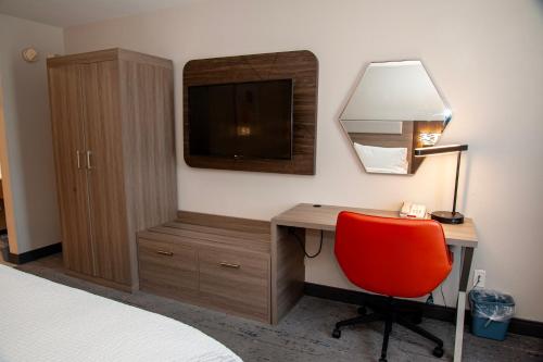a bedroom with a desk with a television and a red chair at Holiday Inn Express Tucson-Airport by IHG in Tucson