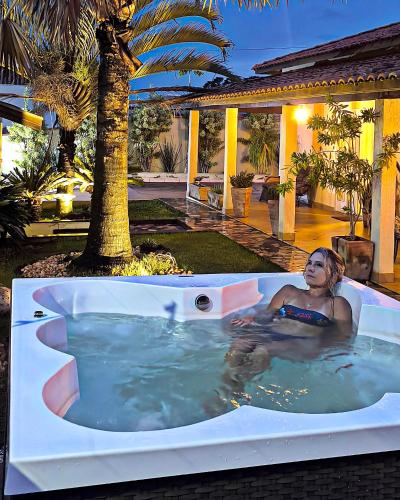 a woman in a jacuzzi tub in a backyard at Spa Belo Quinto Prime in Brotas